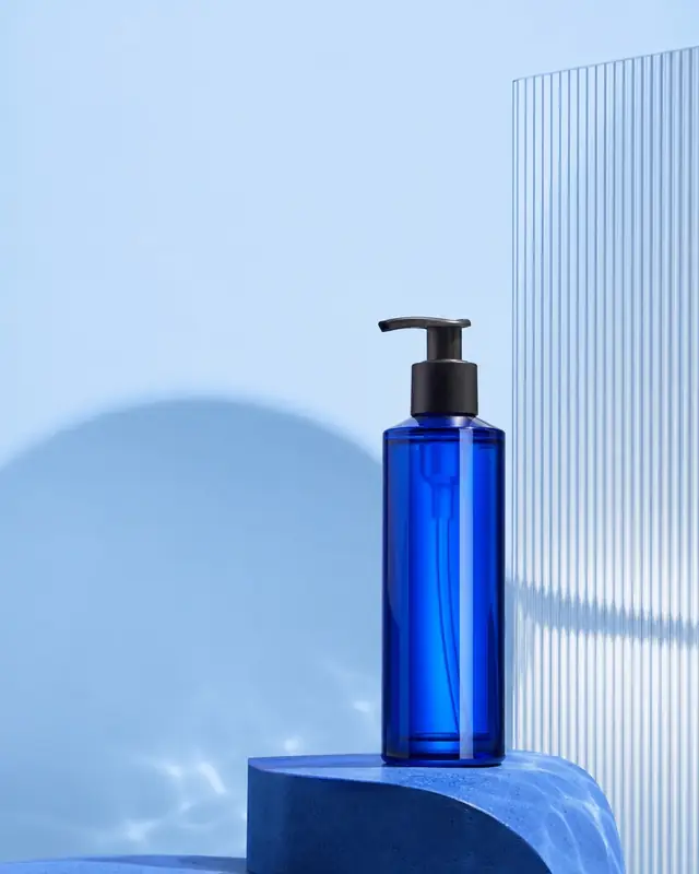 Cobalt-blue skincare bottle in a pale blue studio